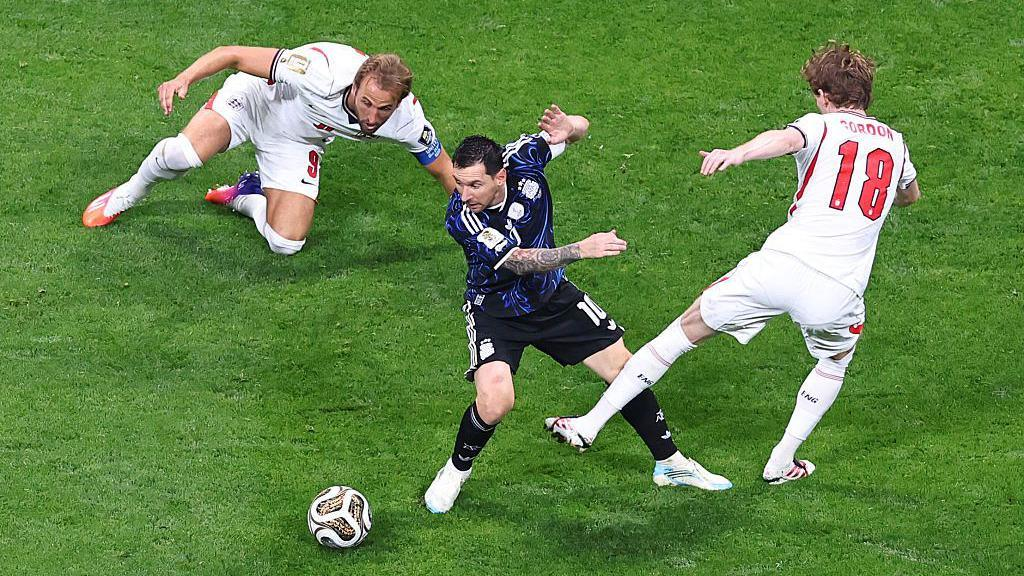 Lionel Messi dribbles between Harry Kane and Anthony Gordon during the World Cup semifinal